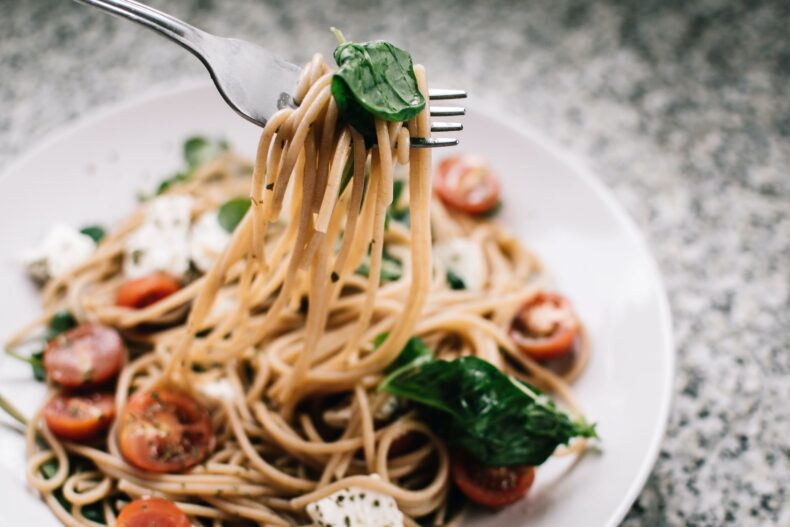 A bowl of pasta with tomato and basil
